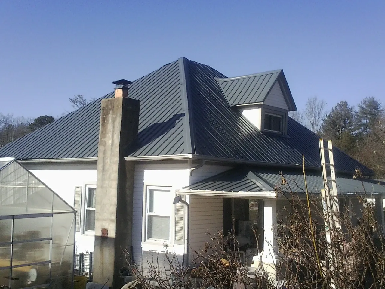 Dark blue standing seam metal roof on a white farmhouse with dormer — Slate & Tile Roof Repair by Roofing Brothers in Barberton