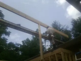 Carpenter setting a ridge beam over a new addition frame — Ice Dam Removal by Roofing Brothers in Barberton