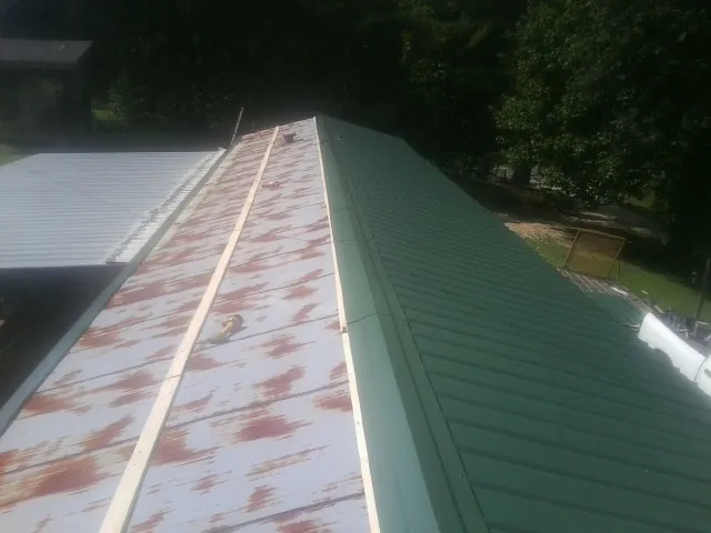 Old rusted panels beside newly installed green metal roofing — Wind Damage Roof Repair by Roofing Brothers in Barberton