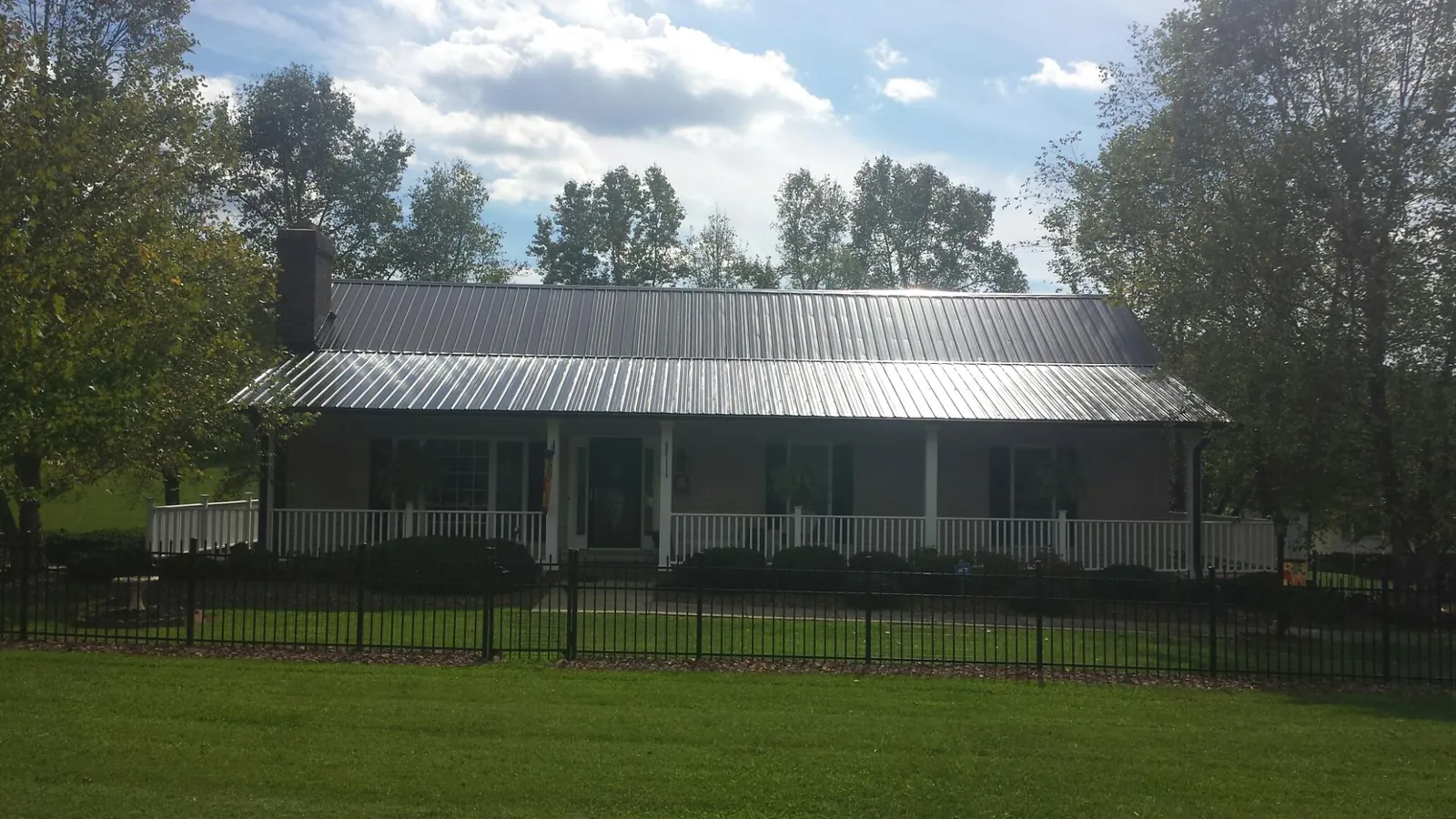 Gray metal roof on a brick ranch with a full width front porch — Gutter Guard Installation work by our crew in Barberton