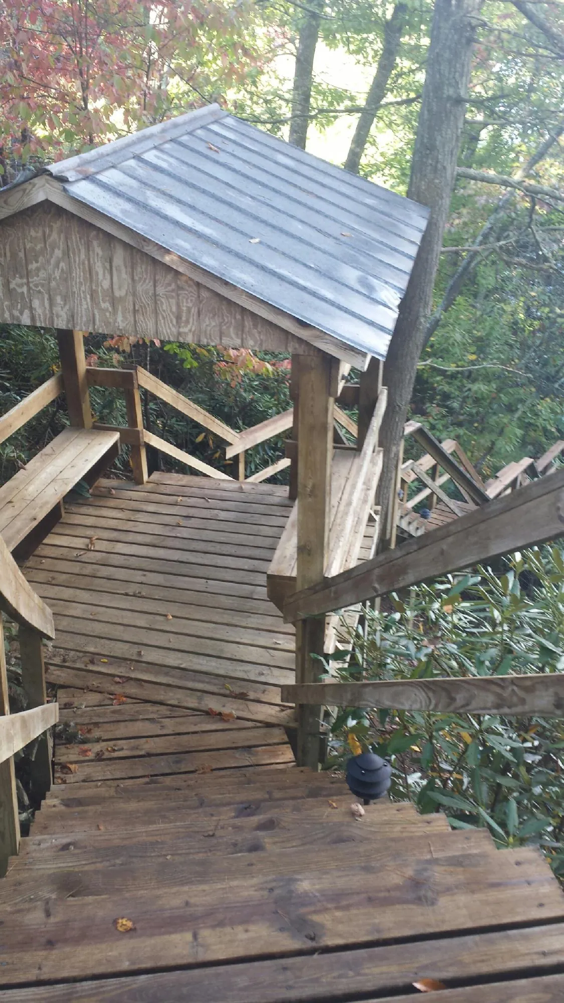 Metal roofed shelter over wooden steps on a wooded walkway — Skylight Repair & Installation work by our crew in Barberton