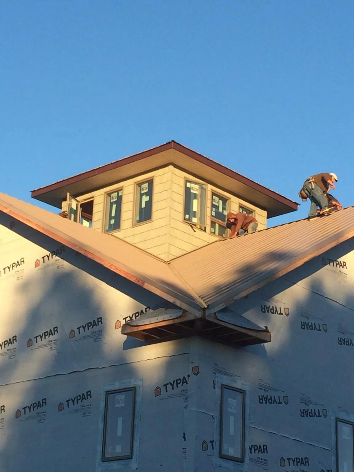 Roofers working around a rooftop cupola on a new metal roof at sunset — Roof Waterproofing in Barberton by Roofing Brothers